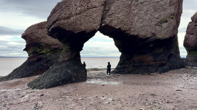 Hopewell Rocks Park in New Brunswick, on a cloudy day. People walking among the rocks, slow motion. Cloudy day, autumn, low tide in the park. National reserve of Canada. The most beautiful places in