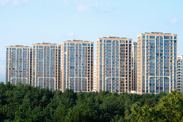 Fototapeta premium Residential skyscrapers in an urban area with natural green foreground. Panoramic view of high-rise residential buildings surrounded by greenery, modern architecture and urban living lifestyle