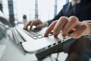 Closeup image of a man working and typing on laptop computer keyboard