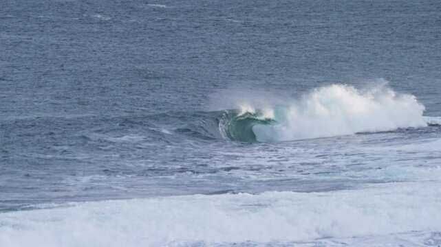 Smooth barrel wave forms in the Atlantic, rolling forward slowly on a stormy day