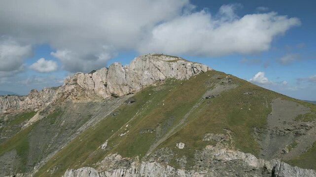 Korab Mountain peak on a sunny day in Albania with rocky cliffs and rolling green slopes