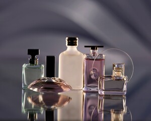 Elegant display of various perfume bottles on a reflective surface with a soft gradient background.