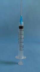 Standing syringe isolated on blue background