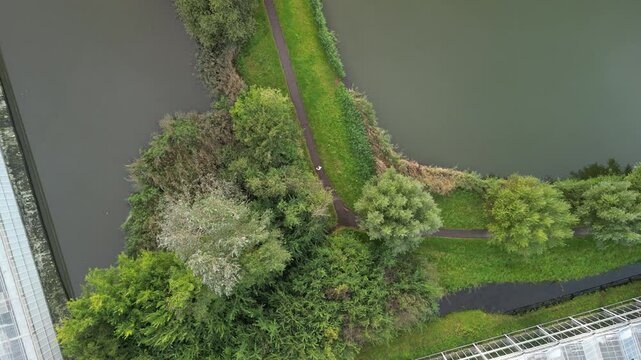 Drone footage over a green path with lush green vegetation on river