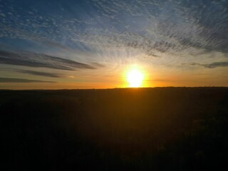 Stunning sunset over a vast landscape with dramatic clouds and a glowing horizon.