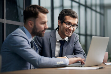 Fototapeta premium Two young businessmen sitting at workplace and working together in office