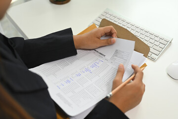 Close up of businesswoman analyzing important documents at desk