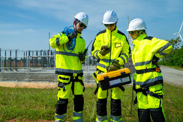 An engineer wearing safety gear closely inspects the base of a wind turbine in a renewable energy...