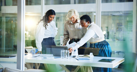 Obraz premium Business women, discussion and documents with laptop for company statistics, analysis or project ideas at office. Female people, employees or colleagues with computer for budget review or performance