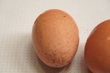A close-up view of a single brown egg on a white surface.