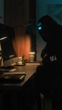 Vertical view of Black male criminal stealing computer mouse, keyboard and monitor from wooden desk while carrying out apartment heist