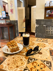 toast and a glass of iced black coffee on a vintage tile table. Vintage style cafe shop interior. selective focus
