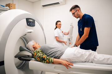 Medical staff positioning elderly woman for a CT scan procedure