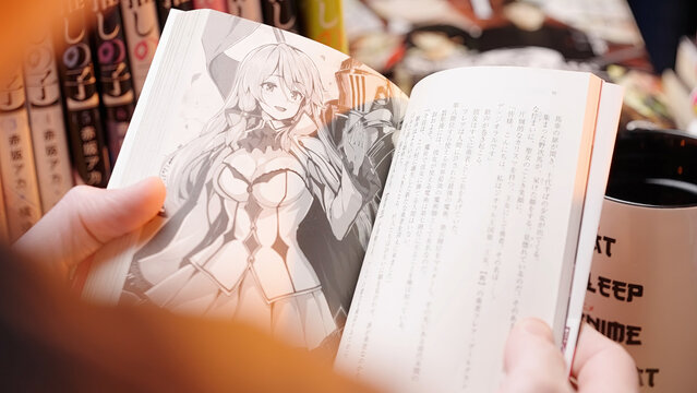 Person read Japanese dark fantasy light novel Redo of Healer, closeup on black and white art