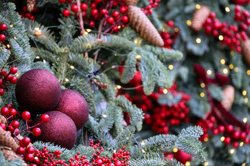 New Year background, Christmas tree branches with red balls and cones on blurred lights background