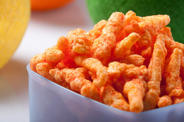 Spicy crunchy puffcorn snacks filling a small bowl on white background