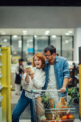 Happy couple choosing jarred food while shopping in supermarket