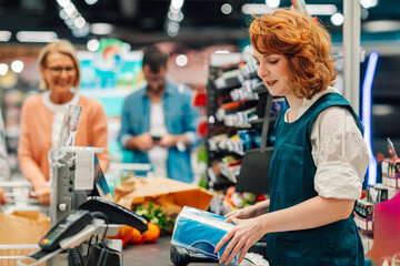 Cashier scanning groceries at supermarket checkout,