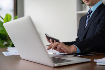 Businessman Working on Laptop with Calculator and Notes