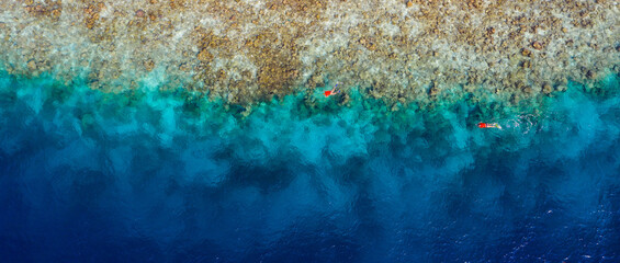 Cropped top above high angle aerial drone view of pure blue ocean water washing mountain rock stone two people diving exploring coral reef luxurious destination tour tourism egypt turkey