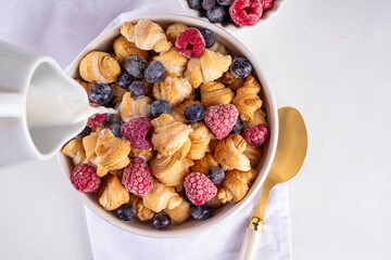 Tiny breakfast croissant cereals with fresh berries and milk
