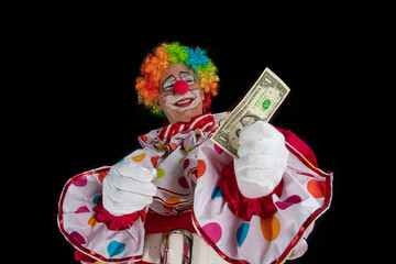 Funny clown with one dollar. Man entertainer as Joker in a suit and wig, with clown whiteface...