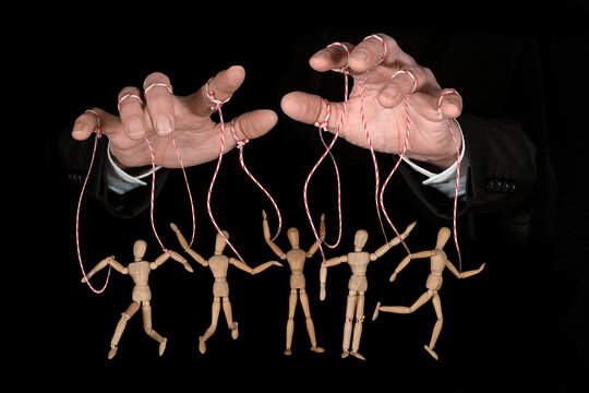 Wooden puppet doll, obeying master  hand pulling the strings of dancing marionette