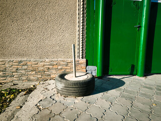 A tire is sitting on the ground next to a green door. The tire is old and worn, and it seems to be a discarded item. The scene has a somewhat abandoned or neglected feel to it