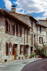 A charming cobblestone street in medieval Assisi, (Umbria, Italy), featuring ancient stone buildings and vibrant flower pots