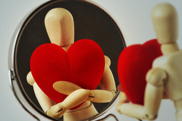 Wooden mannequin with heart looking at himself in the mirror - Love yourself concept