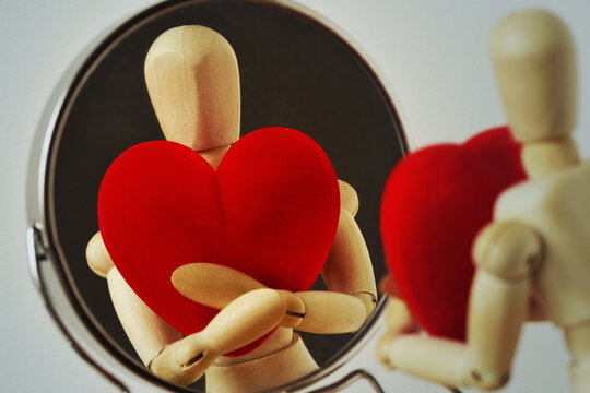 Wooden mannequin with heart looking at himself in the mirror - Love yourself concept