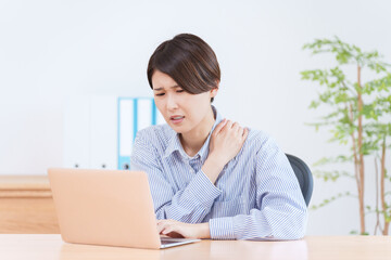 パソコンで仕事する肩凝りの女性