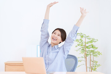 パソコンで仕事する万歳した女性