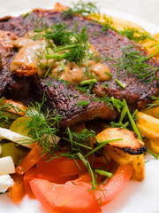 Dinner with premium t bone steak, fried potatoes chips with ridge, fresh salad with feta cheese on white plate and light color table cloth. Large portion of food with high quality products.