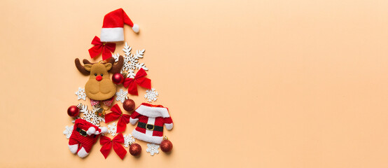 Christmas tree made from colored suit santa decoration on colored background, view from above. New Year minimal concept with copy space