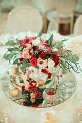 Floral centerpiece with roses and pomegranate on mirrored table