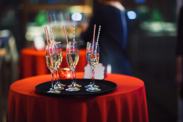 Elegant champagne glasses with straws on festive table