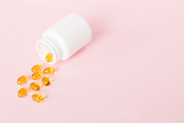 Soft gels pills with Omega-3 oil spilling out of pill bottle close-up. Gel capsules bottle white...