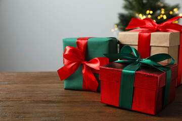Beautiful gift boxes tied with bows, Christmas tree on wooden table