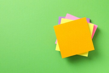 Top view of stack of colorful sticky notes on green background 