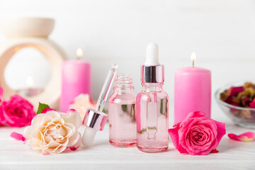 Rose essential oil on a textured background.Roses and a bottle of rose perfumed water.Aromatherapy treatment. Beauty concept. Spa procedure.Natural organic oil.Anti-stress,detox relax.Place for text