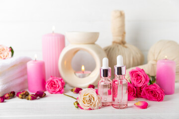 Rose essential oil on a textured background.Roses and a bottle of rose perfumed water.Aromatherapy treatment. Beauty concept. Spa procedure.Natural organic oil.Anti-stress,detox relax.Place for text
