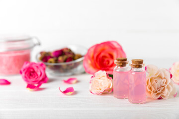 Rose essential oil on a textured background.Roses and a bottle of rose perfumed water.Aromatherapy treatment. Beauty concept. Spa procedure.Natural organic oil.Anti-stress,detox relax.Place for text