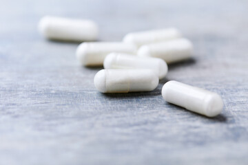 Beta-alanine capsules. Bodybuilding food supplements on wooden background. Soft focus. Close up. Copy space.	