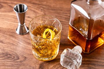 Old fashioned cocktail garnished with orange on wooden table