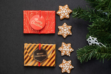 Homemade gingerbread cookies with gifts for the new year and a Christmas tree on a dark background. Top view