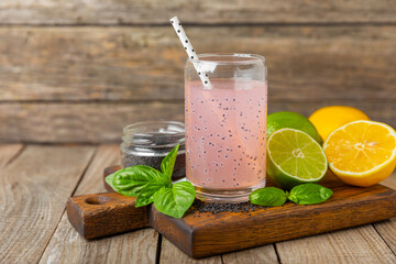 Diet detox cocktail with basil and chia seeds in a glass jar and a glass on a textured background....