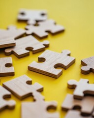 Fototapeta premium wooden puzzles on a yellow background close up soft focus.