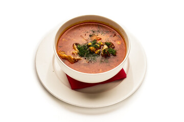 A bowl of soup with a red napkin on top of a white plate