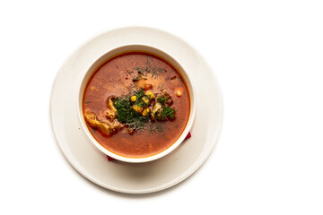 A bowl of soup with a red napkin on top of a white plate